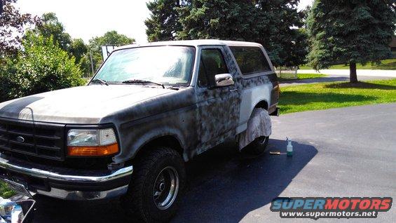 Ford Bronco with primer and body filler on the passenger side, parked in a driveway