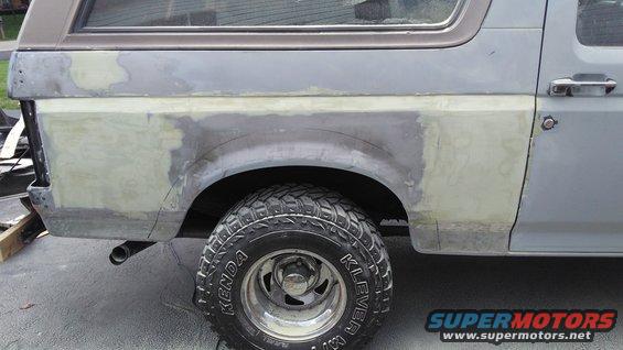 Side view of vehicle's rear quarter panel with body filler and primer