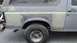 1996 Ford Bronco - The rear quarter panel of a vehicle shows extensive bodywork in progress, with primer and filler applied over damaged areas.