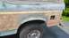 1996 Ford Bronco - The rear quarter panel of a Ford Bronco is shown with primer and filler, indicating repair work is in progress.