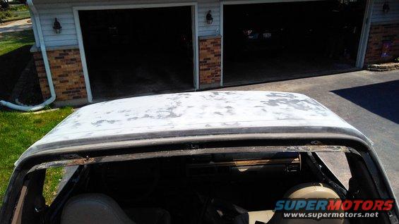 view from inside old SUV, looking at peeling paint on roof, garage in background