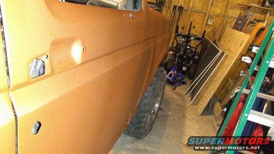 Orange vehicle door and tire in a garage with tools and lumber