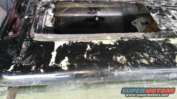 Black tailgate with peeling paint and exposed metal. Part of a vehicle