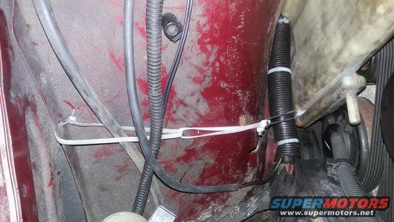 Close-up of red car's engine bay wiring harness secured with zip ties