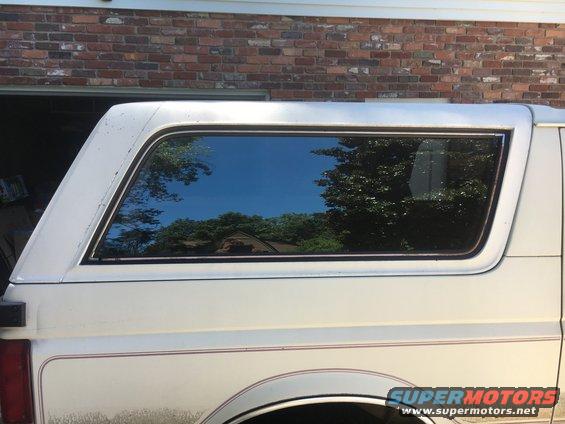 White SUV side view, showing a portion of the rear passenger window and trim