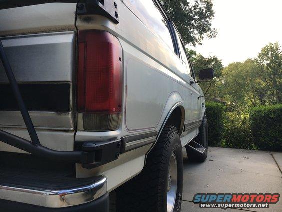 White SUV rear quarter panel with red taillight and chrome bumper