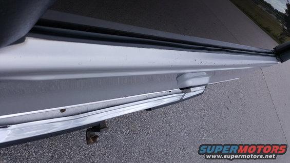Close-up of a vehicle's rear bumper corner showing a tow hitch receiver