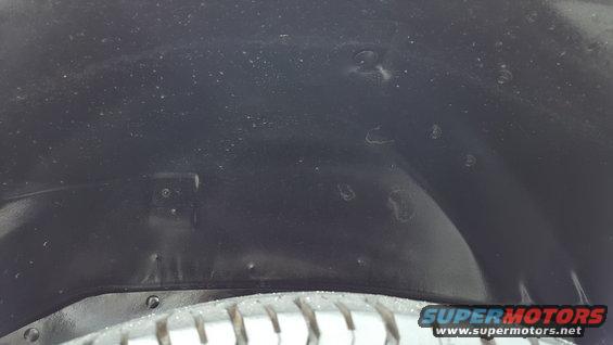 Dark wheel well liner with visible rivets and tire tread