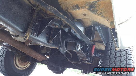 Underside view of a vehicle's suspension and exhaust system, showing leaf springs and a differential