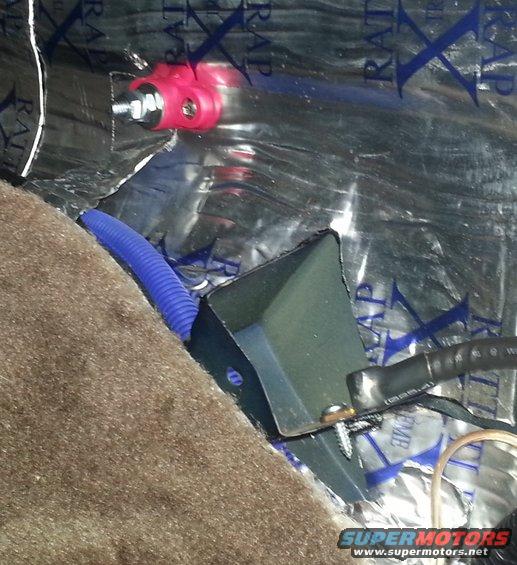 Car interior showing sound dampening material on the wall, a blue wire conduit, and electrical components