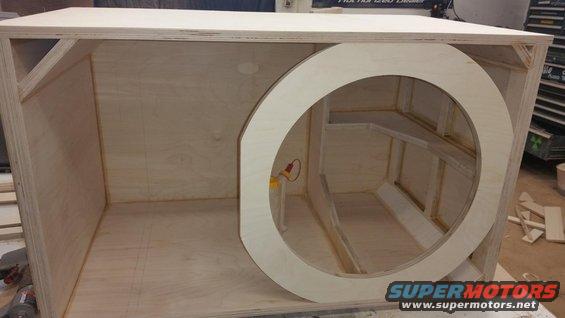Wooden subwoofer enclosure with a large circular cutout and internal bracing