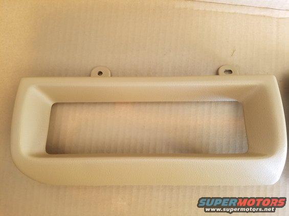 Beige plastic dashboard trim piece with a rectangular cutout and two mounting holes