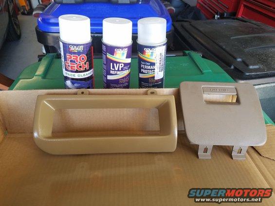 Tan dashboard trim pieces and spray cans on a surface
