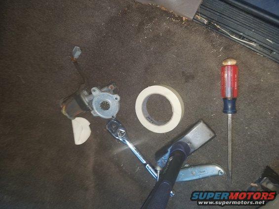Window motor, tape, ratchet, and screwdriver on carpet