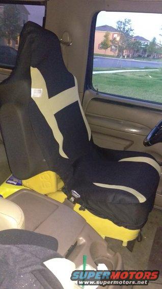 Car interior showing a black and tan seat cover over a tan seat, with yellow containers underneath