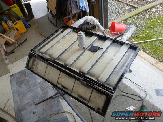 Car hardtop on stand with spray can and rag on top, undergoing painting
