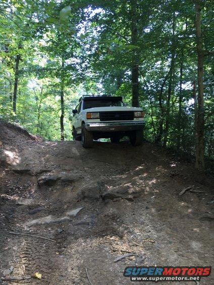 1988 Ford Bronco climbing a steep, rocky, wooded trail
