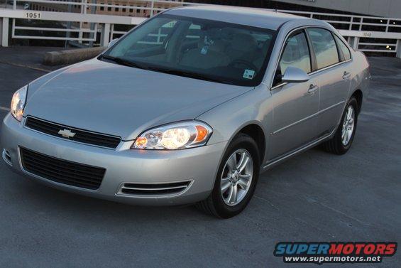 Silver sedan parked on a concrete surface. The front end is visible, showing the grille and headlights