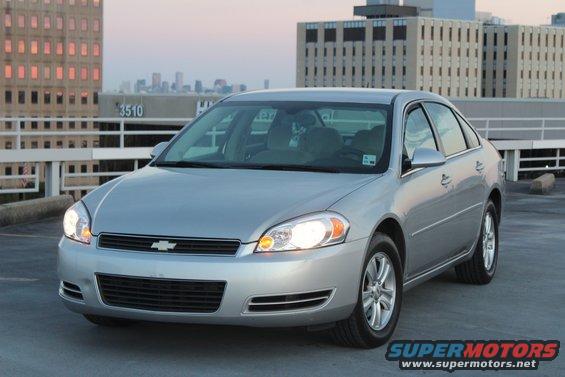 Silver sedan parked on a rooftop, front 3/4 view. Buildings in background