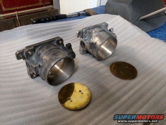 Two throttle bodies and brass plates on a padded surface