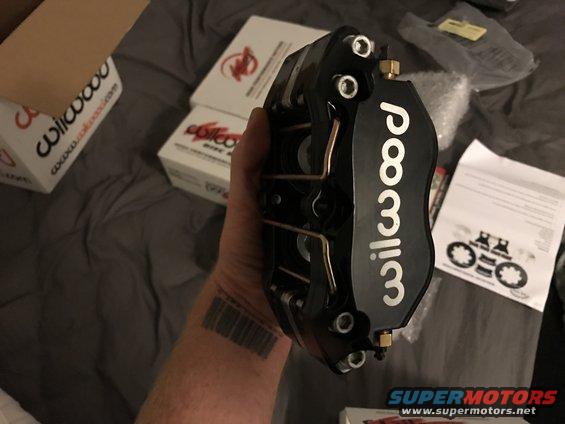 Black Wilwood brake caliper held in hand, boxes in background
