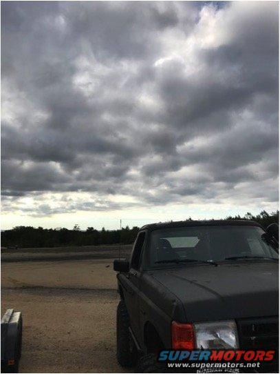 1989 Ford Bronco parked on dirt under cloudy sky