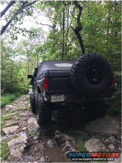 1989 Ford Bronco rear view, black soft top, spare tire on back, off-roading
