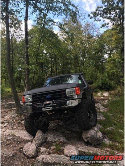 1989 Ford Bronco on rocks, front winch visible. License plate 403-2L7
