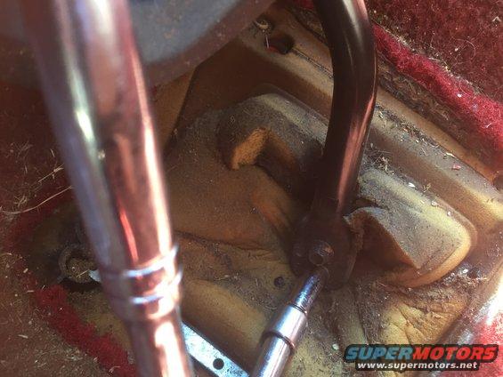 Socket wrench on bolt near floor shifter linkage, red carpet visible