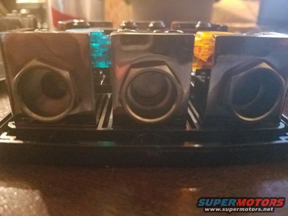 Close-up of a car stereo power distribution block with three ports, two with blue and orange fuses