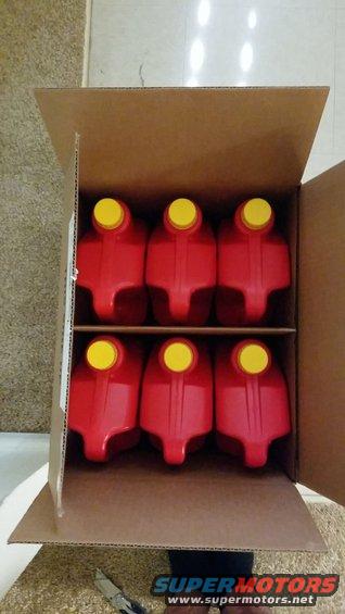 Six red oil jugs with yellow caps in a cardboard box. Supermotors.net logo visible