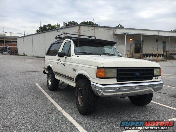 White 1988 Ford Bronco with roof rack parked in a lot