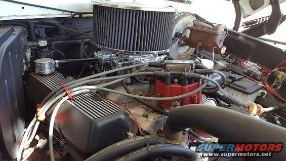 engine bay with aftermarket air filter, carburetor, and red distributor cap