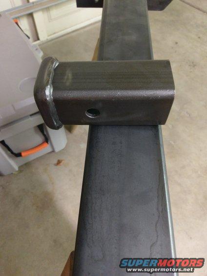 Trailer hitch receiver tube with a welded cap and a pin hole