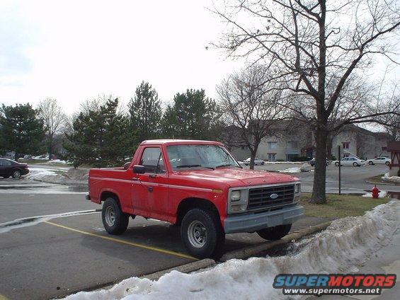 Red pickup truck with a gray grille and chrome Ford emblem