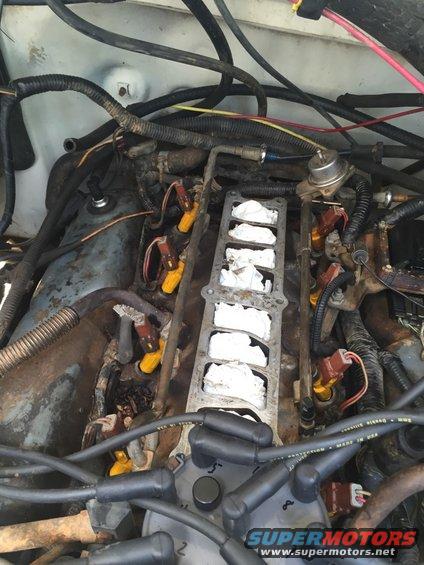 Engine bay showing fuel injectors and intake manifold with white rags stuffed inside