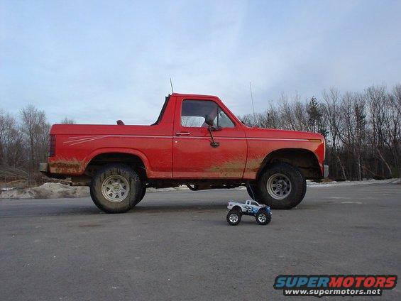 Red 1980 Ford Bronco side view with a toy truck