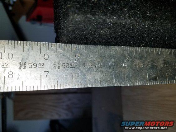 close-up of a metal ruler with inch and fractional inch markings, measuring a black textured surface