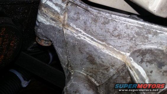 Gray metal engine part with white residue and rust, close-up