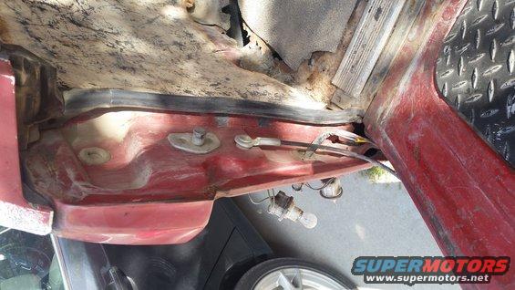 Red vehicle interior with rust and exposed wiring near a light bulb