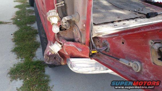 Red 1981 Ford Bronco rear corner with damaged taillight housing and exposed wiring