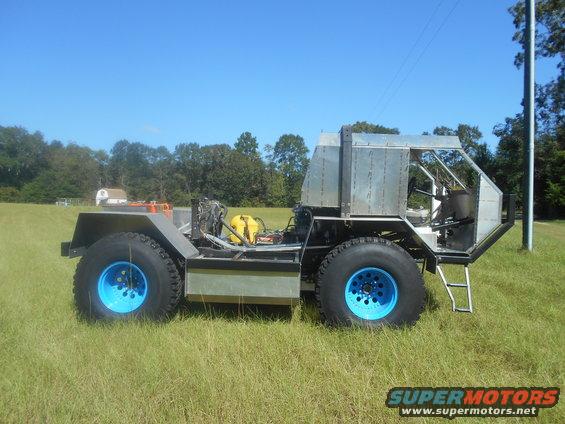 Custom off-road vehicle with large tires and blue wheels, side view