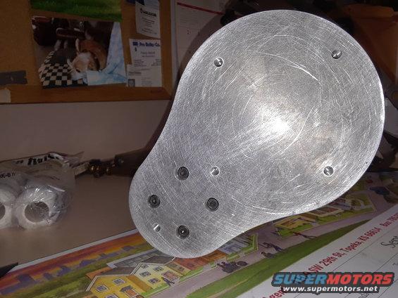 metal disc with screw holes on a table with some papers and tape rolls