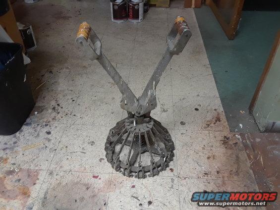 metal tool with two handles and a cage-like bottom, sitting on a dirty floor