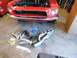 1968 Ford Mustang - A red 1968 Ford Mustang is parked in a garage with new exhaust headers and clutch parts on the floor.