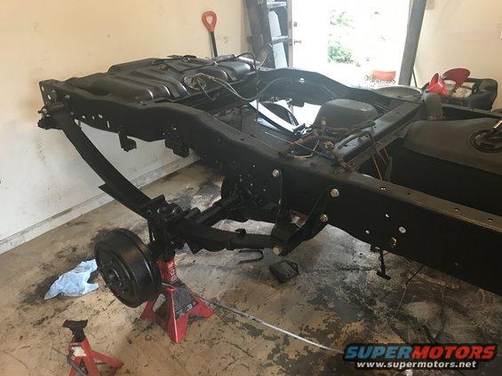Truck frame assembly with fuel tank and suspension parts, on jack stands