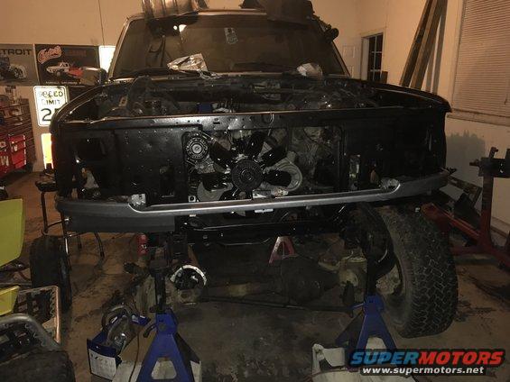 Front view of a 1995 Ford F-150 with the hood and grille removed, showing the engine bay and front suspension disassembled