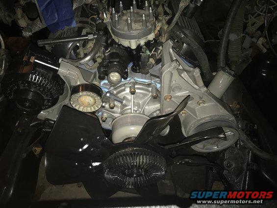 Close-up of a vehicle engine bay showing the alternator, water pump, and fan shroud