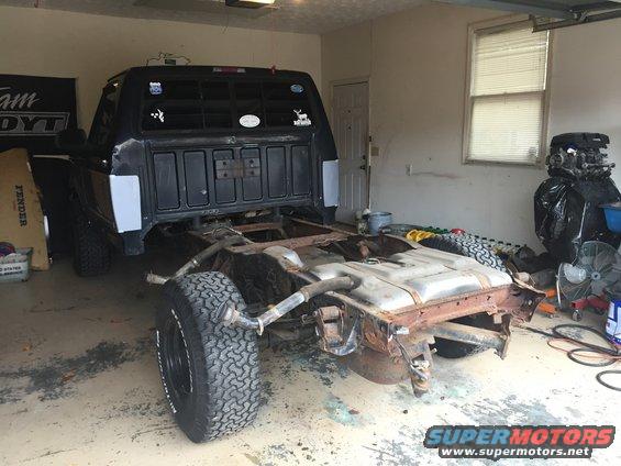 Black Ford F-150 truck chassis with fuel tank removed, viewed from the rear