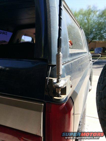 rear corner of dark SUV, showing antenna mount and taillight. Spare tire visible on right